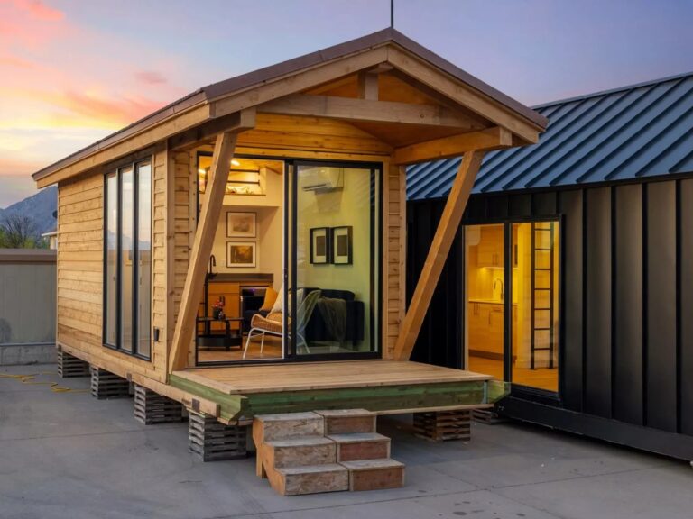 Exterior perspective of Sledhaus 200 tiny home with a wooden facade and glass sliding doors during sunset.