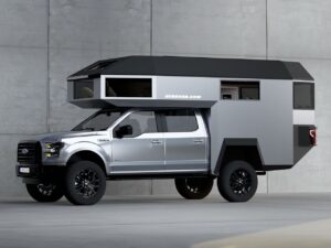 Side view of a silver Ford pickup truck integrated with a GEHOcab EDGE Explorer demountable cabin featuring sharp angular Brutalist design and panoramic windows.