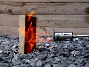 A fire resistance test of a bio-composite sawdust panel showing a gas torch flame directed at the surface without ignition.