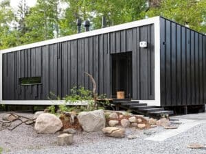 Exterior view of Tiny House Shadow by Matti Kuittinen in Lohja Finland featuring a matte black facade and recycled materials.