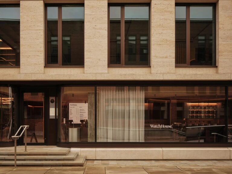 Exterior facade of WatchHouse cafe on the River Thames featuring large glass windows and stone architecture.