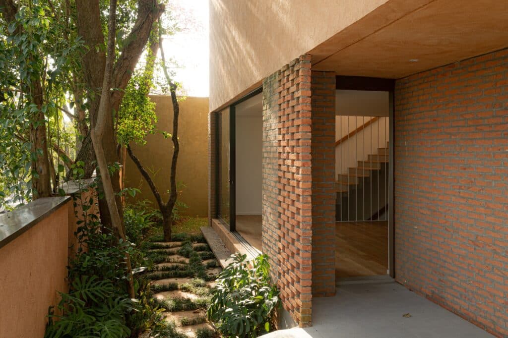 Close-up of a brick wall transition and an outdoor garden path with stepping stones next to the house entrance.