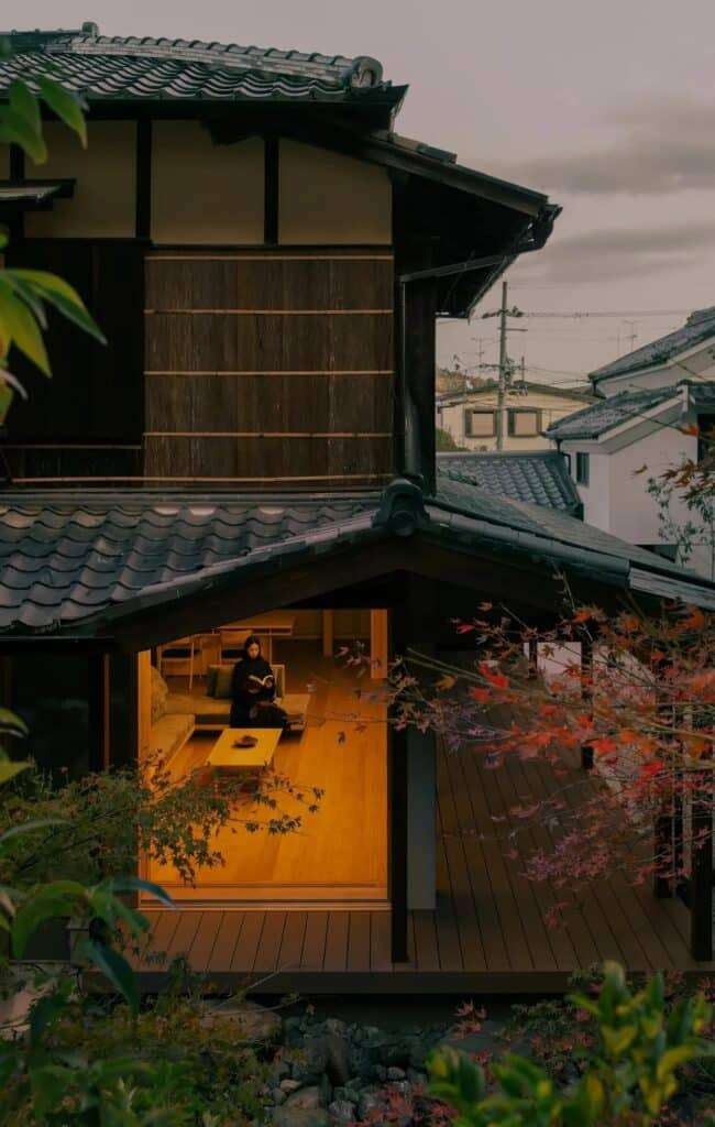 Night view of a restored traditional Japanese house with glowing warm interior lights and a tiled roof in Narutaki, Kyoto.