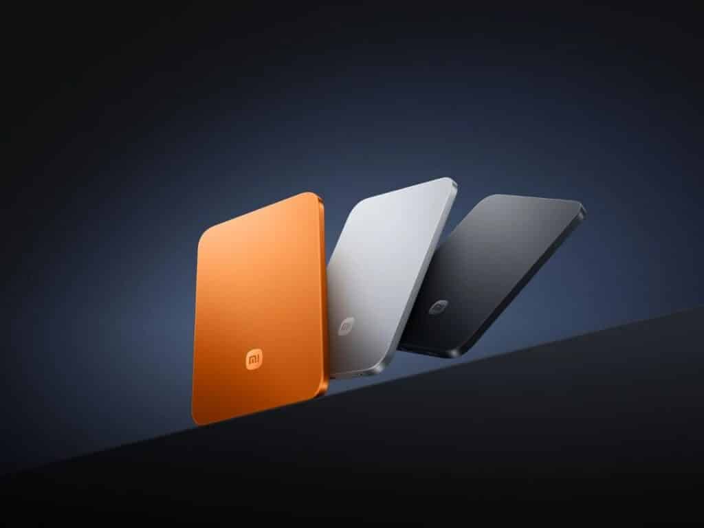 Three ultra-thin Xiaomi magnetic power banks in orange, silver, and dark grey displayed diagonally against a dark background.