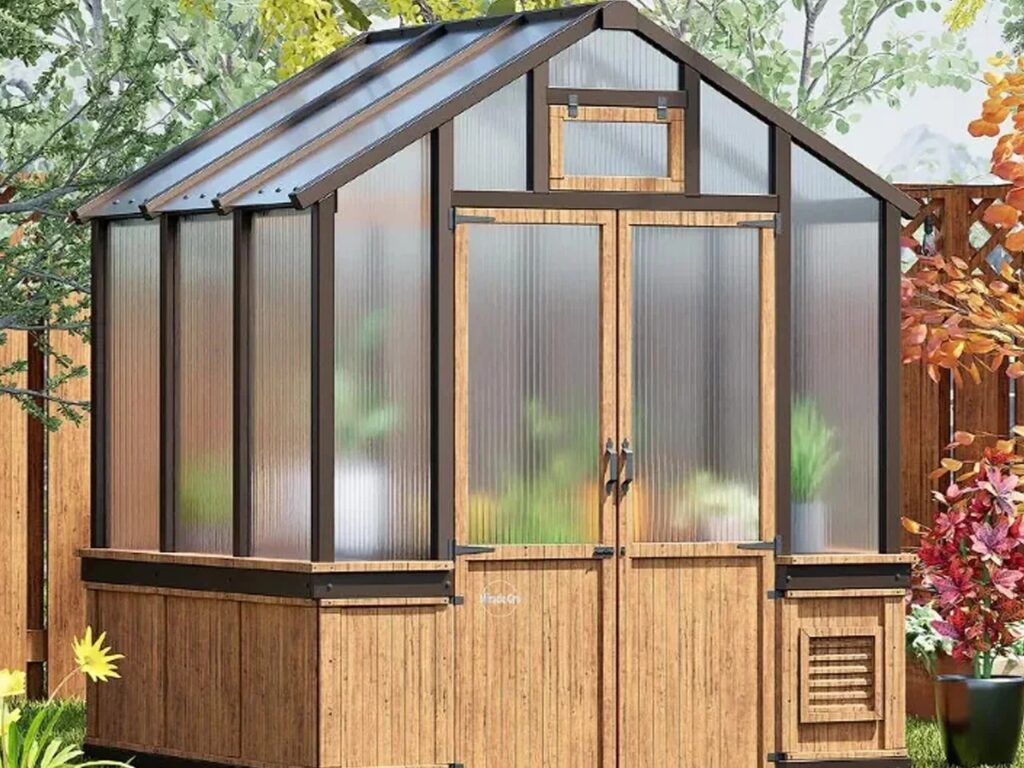A small wooden greenhouse with polycarbonate panels in a backyard setting, showing its compact design for home gardening.