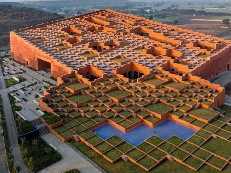 Aerial view of the stepped red brick roof of Prestige University in Indore, showing terraced platforms and green pockets.
