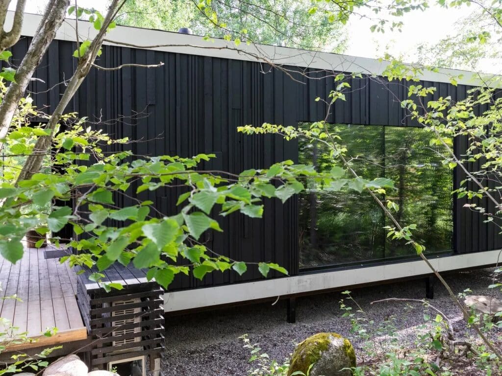 Side view of Tiny House Shadow integrated with Finnish forest nature through large glass windows.