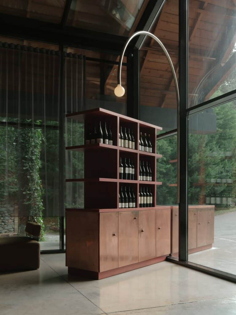 A bespoke copper wine display cabinet standing in front of a floor-to-ceiling glass window.