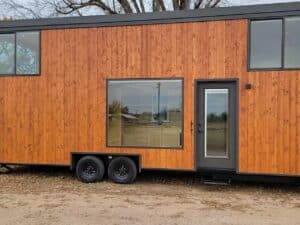 Exterior view of eONE XL Wide & Tall tiny home with cedar wood siding and dual-axle trailer.