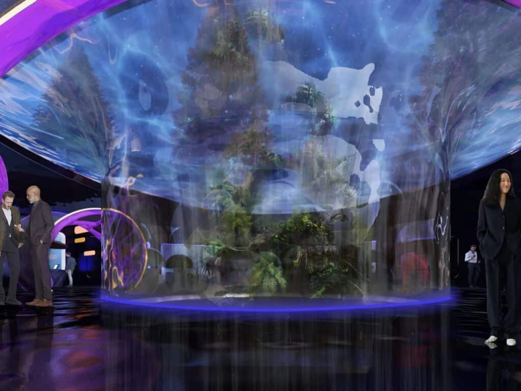 People standing in a dark hall next to a large vertical cylindrical aquarium or terrarium with blue lighting.