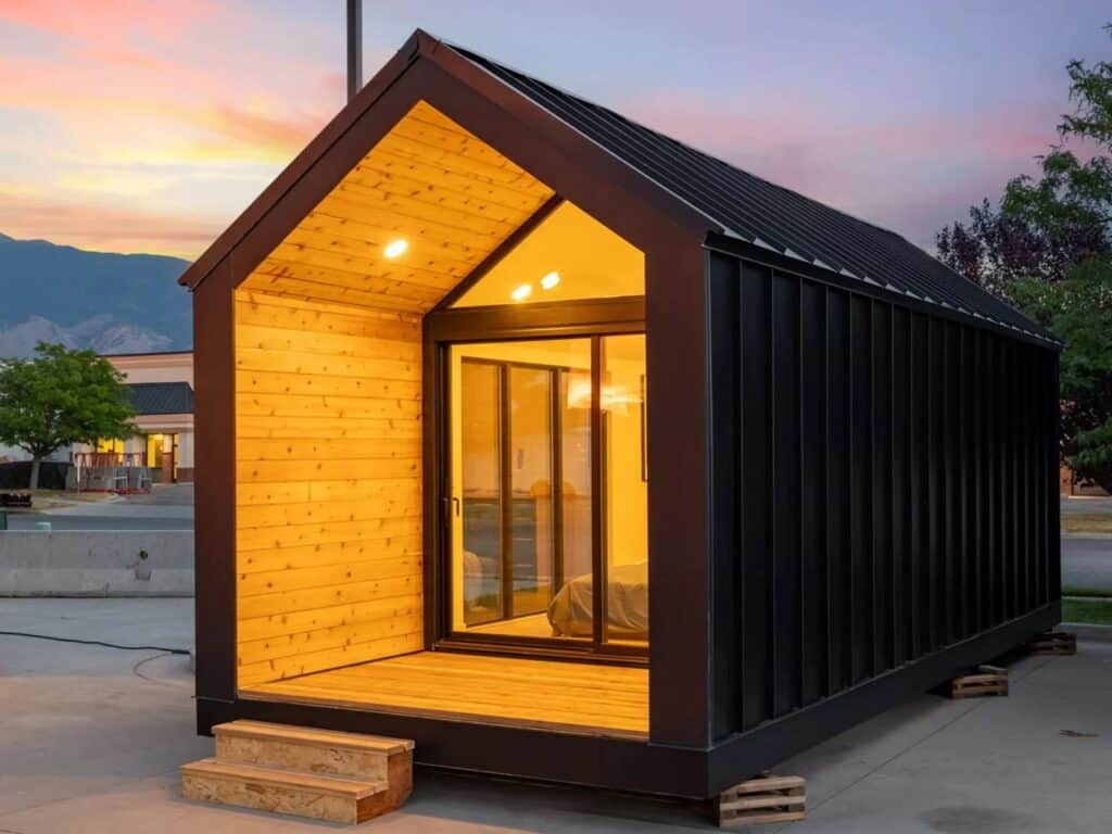 Three-quarter exterior perspective of Mysa 200 showing black metal vertical cladding and a wooden gabled porch.