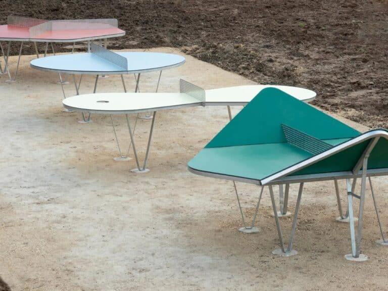 A perspective view of four experimental ping-pong tables with different geometric designs in a schoolyard in Ingré, France.