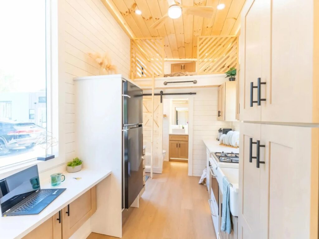 Interior view of Premium Vista showing a linear kitchen with white quartz countertops and a wooden sleeping loft.