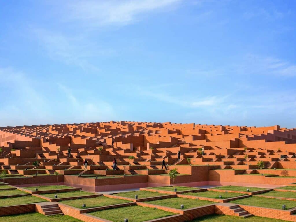 Students walking on the staggered brick terraces of Prestige University under a clear blue sky.