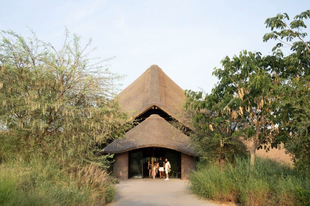 Visitors entering the educational camp at Sharjah Bridi Park under a peaked thatched structure.