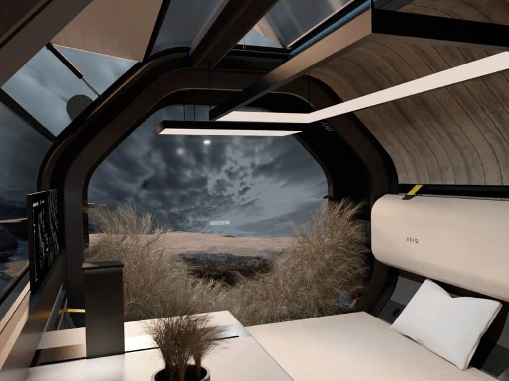 Interior view of HYTTE mobile home featuring a cozy bed, modern lighting, and a large window overlooking a rocky landscape.