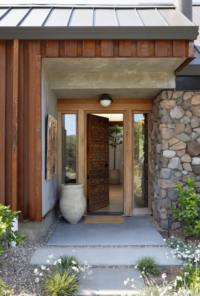 Main entrance of Glen Ellen house featuring a carved wooden door and natural stone walls.