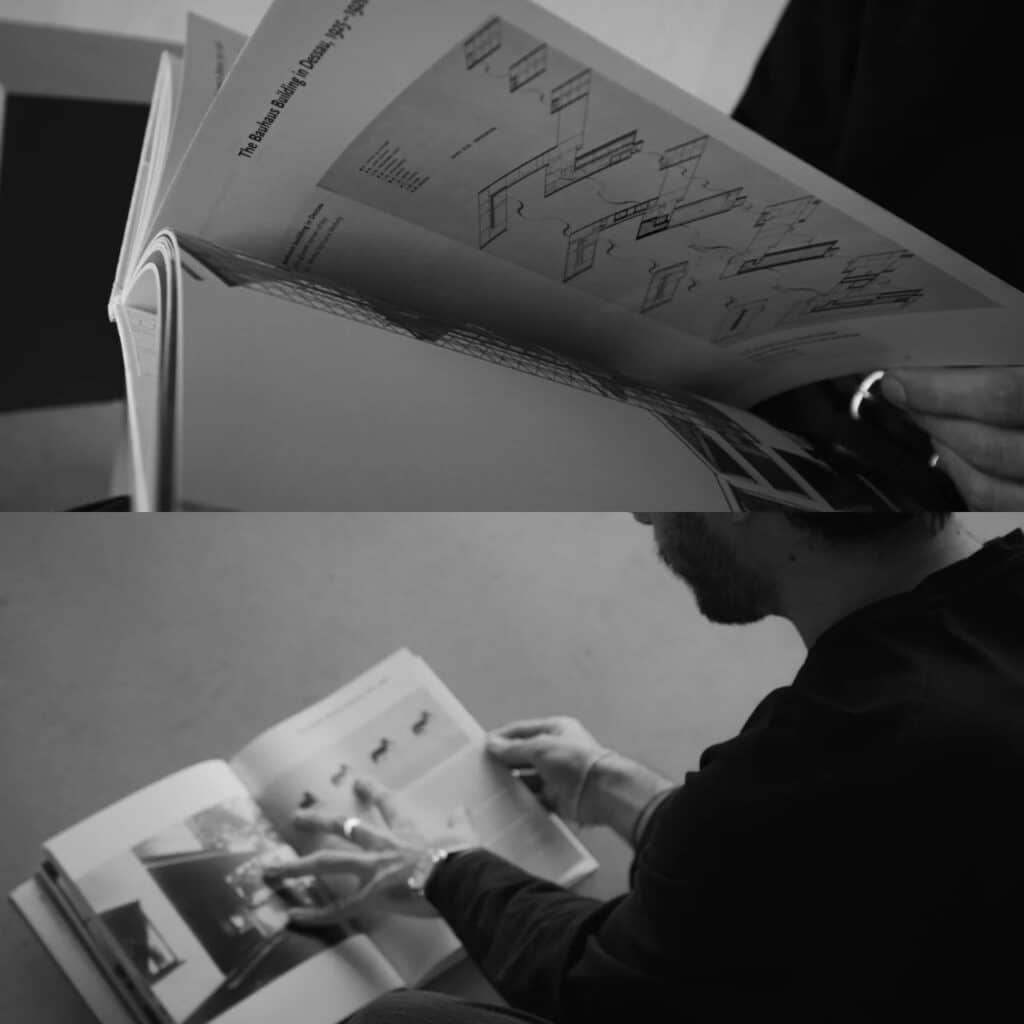 Close-up of a person browsing a book about the Bauhaus Building in Dessau, showing architectural diagrams.