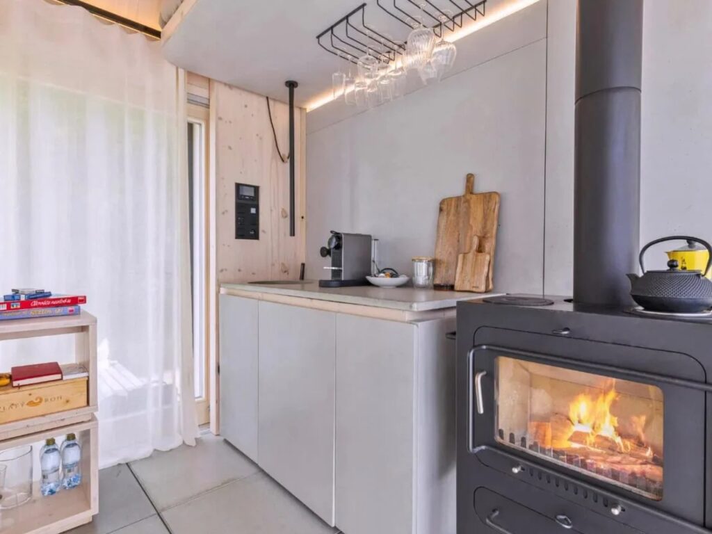 Interior view of Devin Cabin's compact kitchen featuring a wood-burning stove, coffee maker, and smart storage.