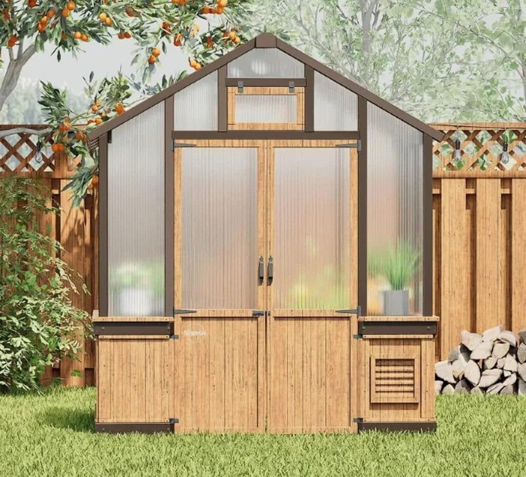 Front view of the wood greenhouse featuring double doors and a top ventilation window against a wooden fence.