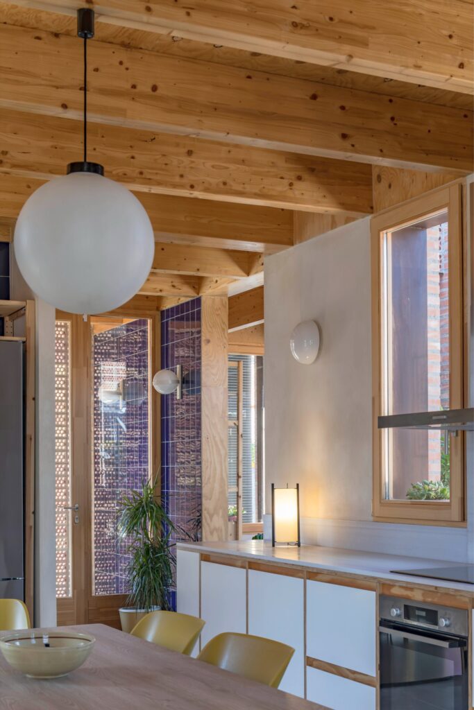 Close-up of the dining area and kitchen in House 1603 featuring globe pendant lighting and ceramic wall details.