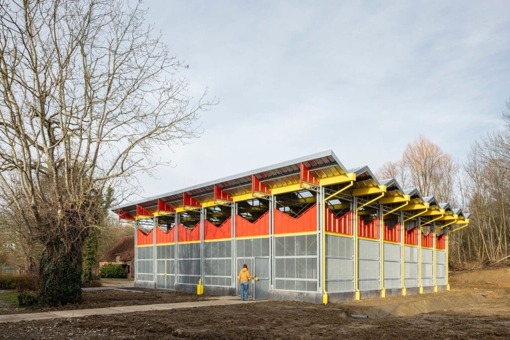 Perspective view of the Research Barn for Aquatic Ecology showing the full length of the red metal infill panels and the surrounding landscape.