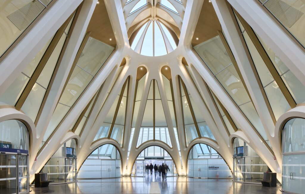 A low-angle shot of a circular glass skylight integrated into the white vaulted ceiling structure of the station.