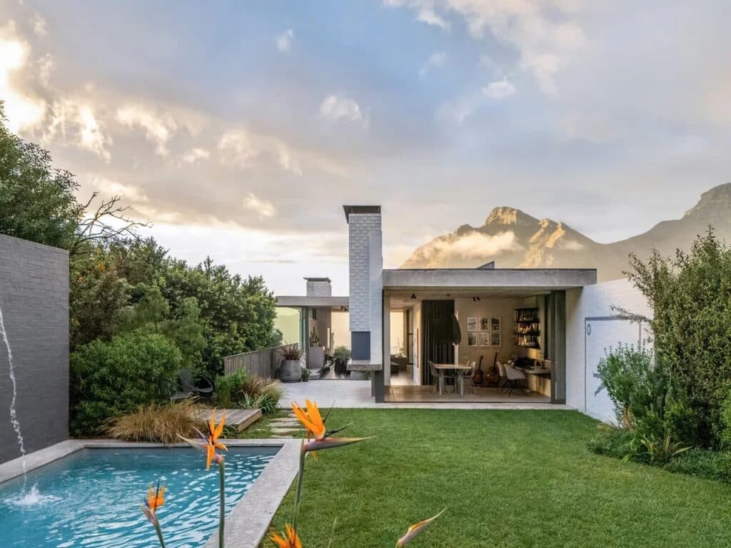 Backyard of Kenmore House featuring a small swimming pool, a green lawn, and an outdoor living area with a mountain backdrop.