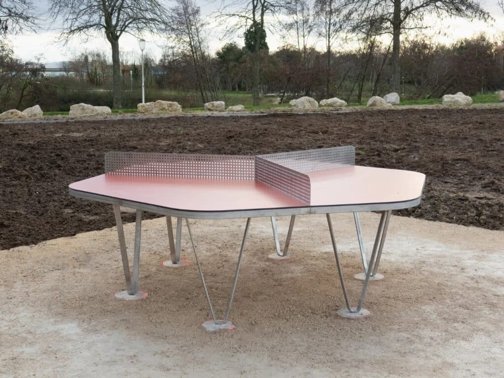 A hexagonal red ping-pong table with a three-way metal net, designed for multiple players.