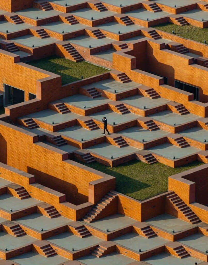 Close-up of a person walking across the terraced brick roof, highlighting the scale of the architectural steps.