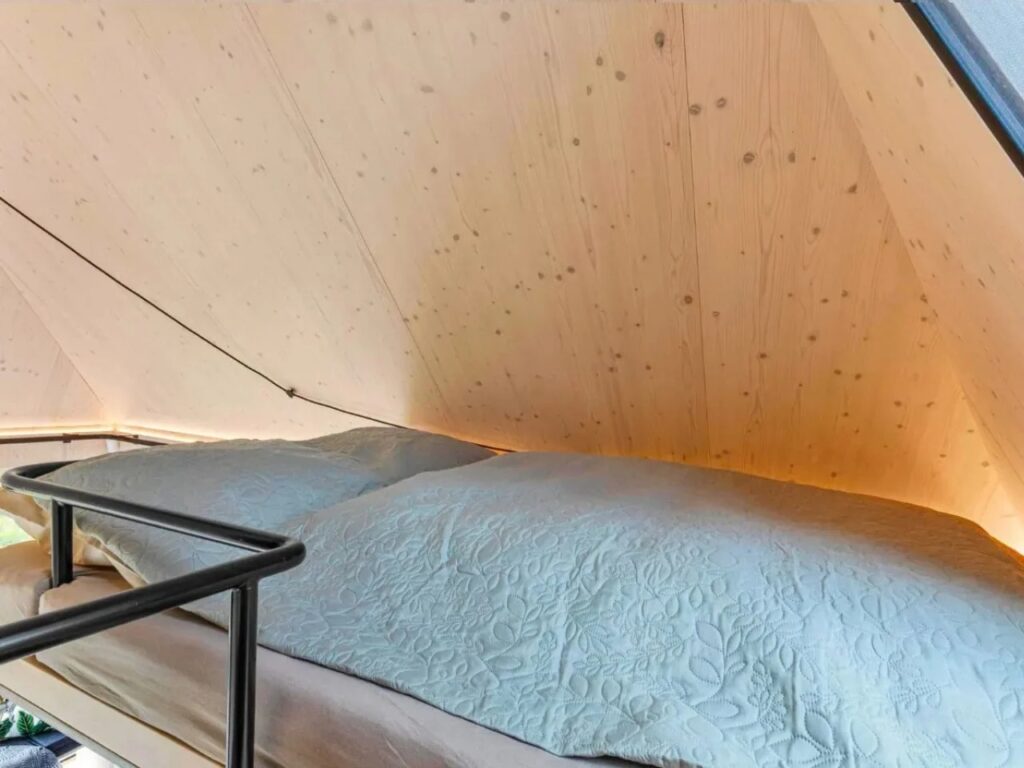 Close-up of the loft sleeping area in Devin Cabin with light wood walls and a cozy bed.