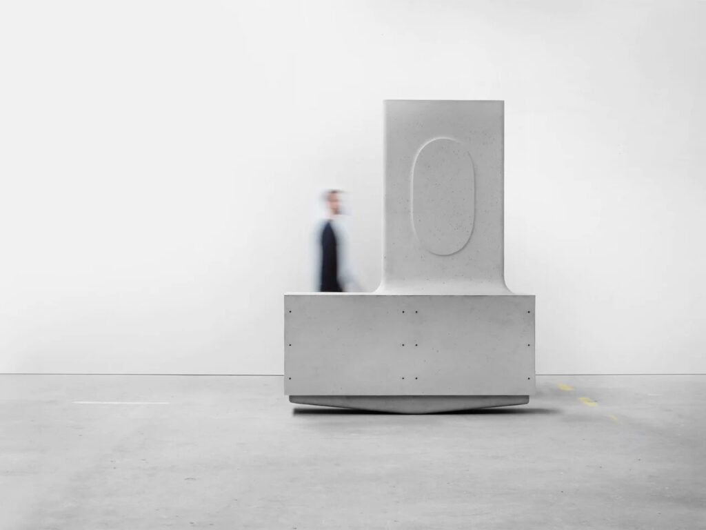 Close-up of a single L-shaped concrete component with an oval indentation on its surface.