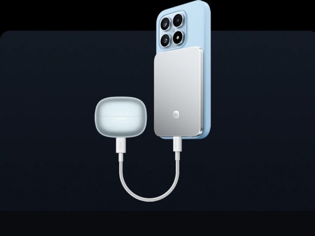 A silver magnetic power bank attached to a blue smartphone while simultaneously charging wireless earbuds via a USB-C cable.