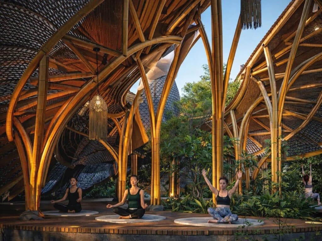 Interior view of the bamboo yoga pavilion showing the radial structural ribs and practitioners in meditation.
