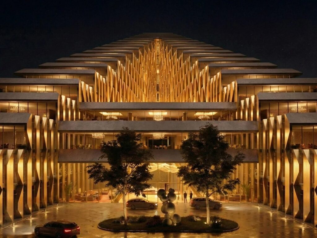 Close-up of the Alatau Iconic Complex facade at night showing the rhythmic golden structural fins and the grand entrance lobby.