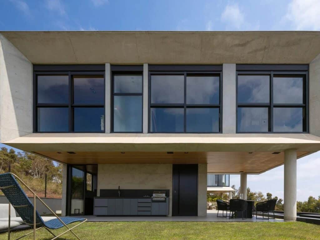 Low angle shot of the GM House concrete structure and outdoor seating area on a green lawn.