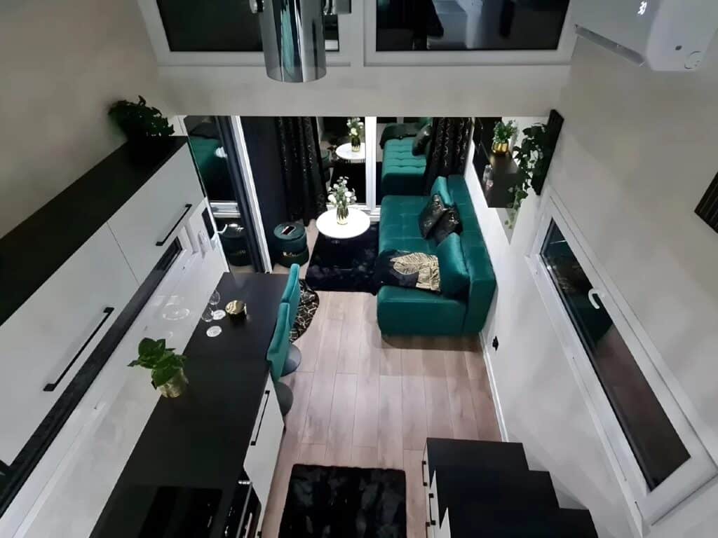High-angle interior view of Erica tiny house living area with green sofa and kitchenette.