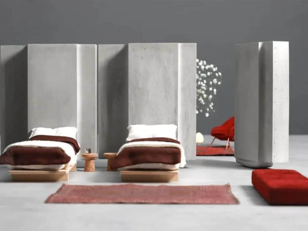 A bedroom layout with two beds separated by modular concrete panels in the Heirloom House project.