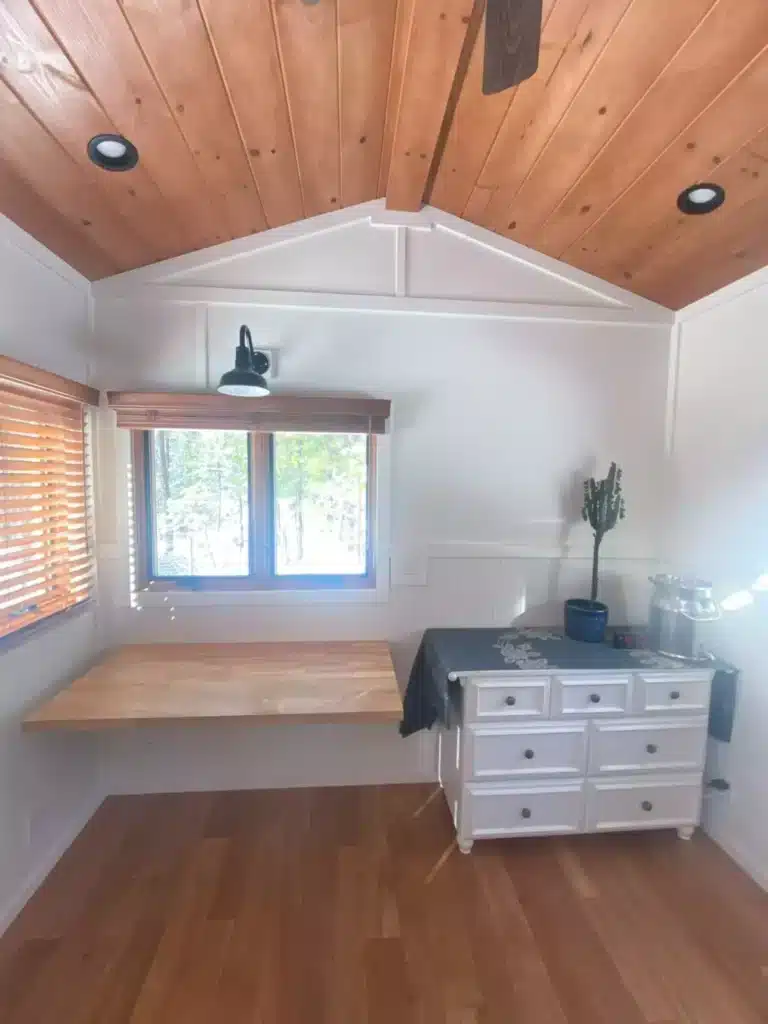 Interior of a small office space with a floating wooden desk, white board and batten walls, and a wooden ceiling.