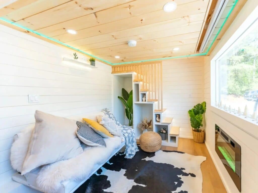 Minimalist living room in Premium Vista with a white sofa, cowhide rug, and integrated storage stairs.