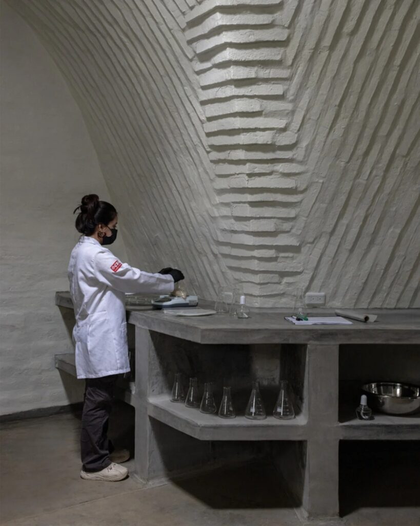 A female scientist working with laboratory scales on a built-in concrete bench inside the vaulted Witocha Lab.