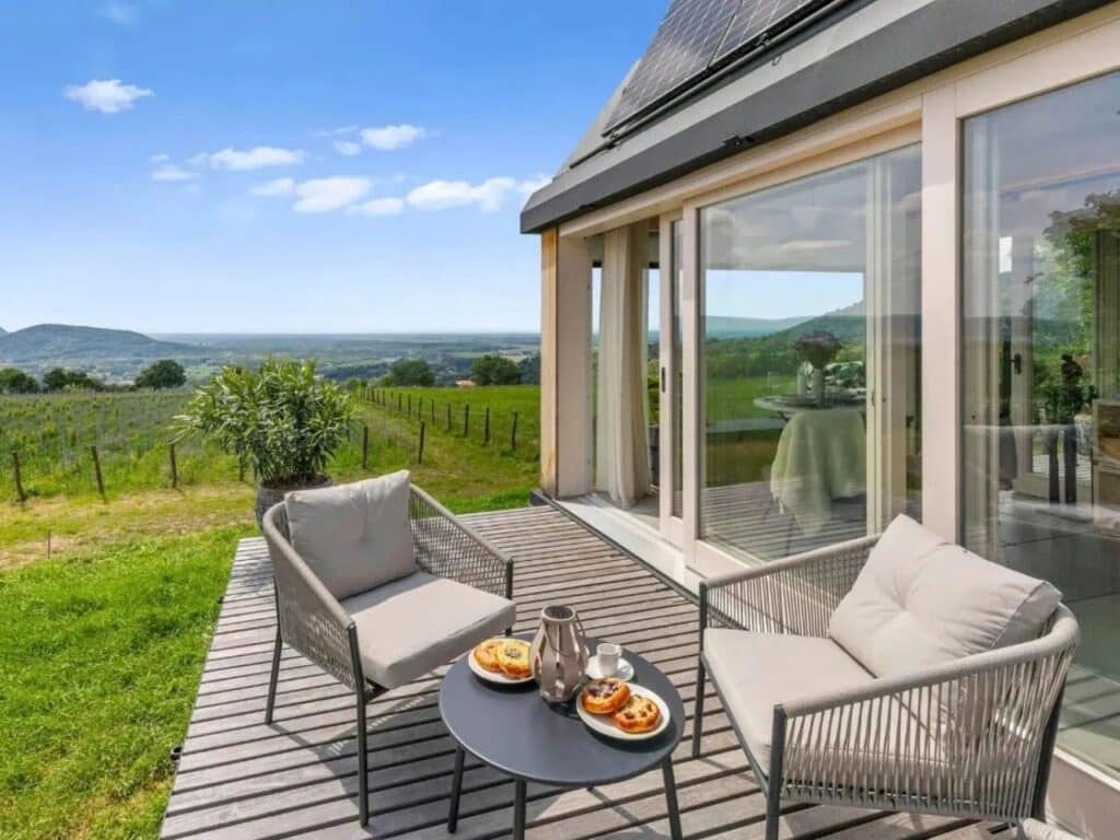 Outdoor seating area of Devin Cabin on a wooden deck with a scenic view of a green valley under a blue sky.