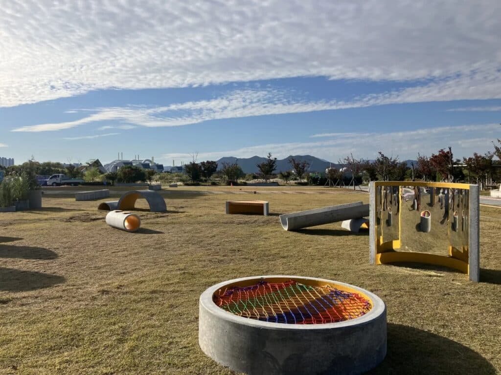 Close-up of a circular concrete base with a colorful rope net and a curved mirror reflecting the surroundings.