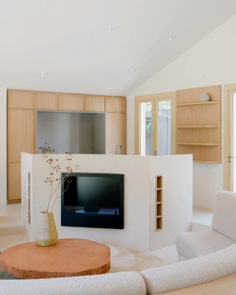 Living area of Seaside House featuring a built-in fireplace, a wooden coffee table, and integrated kitchen cabinetry.