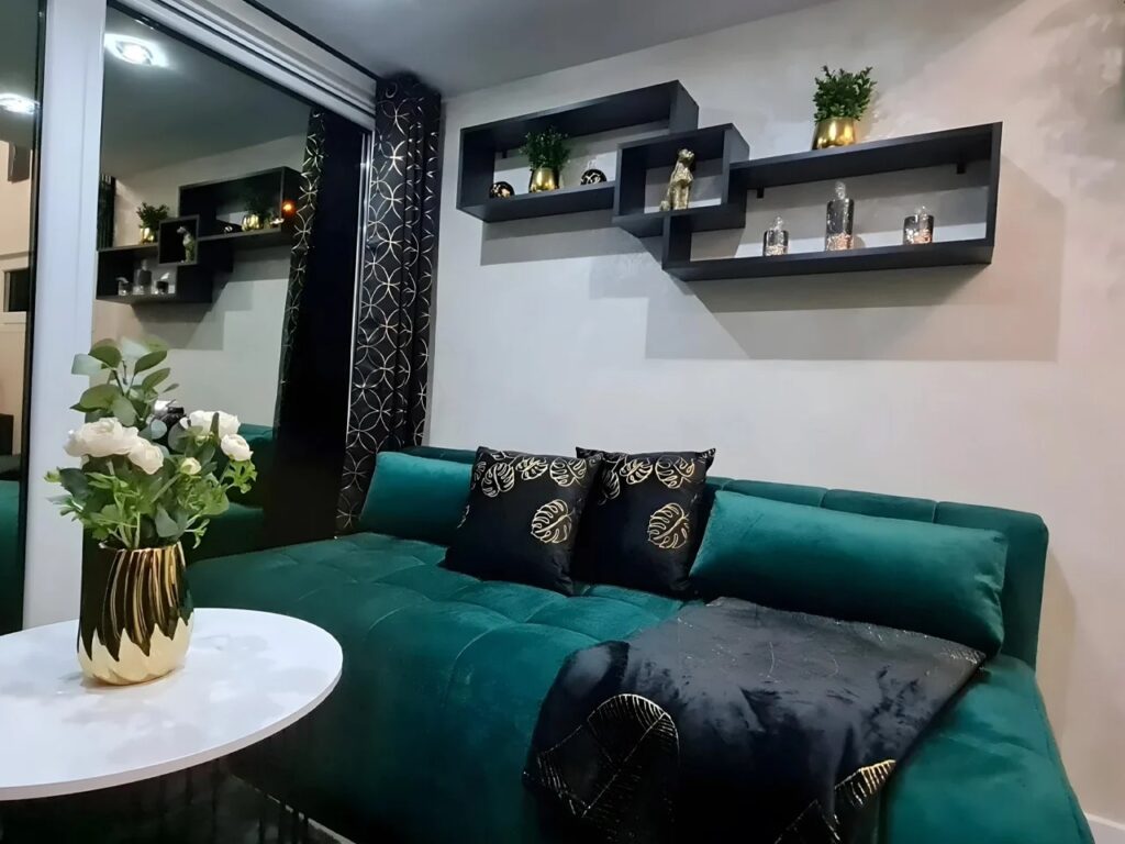Living area of Erica tiny house with modern emerald green sofa and wall shelves.