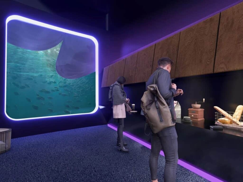 Modern breakroom area with dark finishes and a large screen displaying schools of fish in deep blue water.