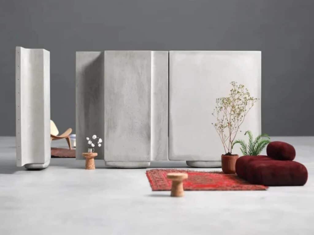 Concrete wall panels joined together without screws, standing behind a red sofa and a plant.