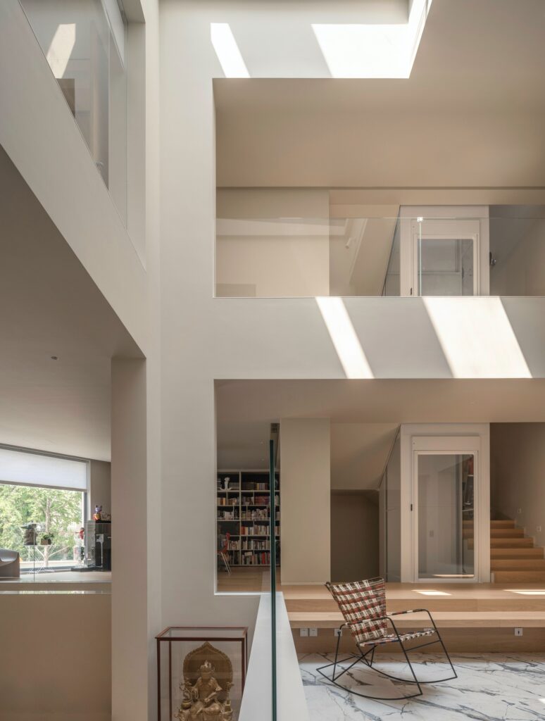 Vertical view of the internal atrium in House of Porous featuring a glass elevator and a multi-level nine-square grid layout.