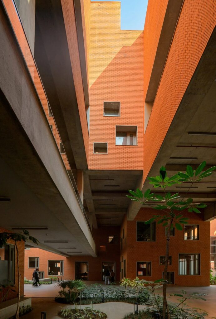Interior view of a high-ceilinged atrium with exposed brick walls and concrete beams.
