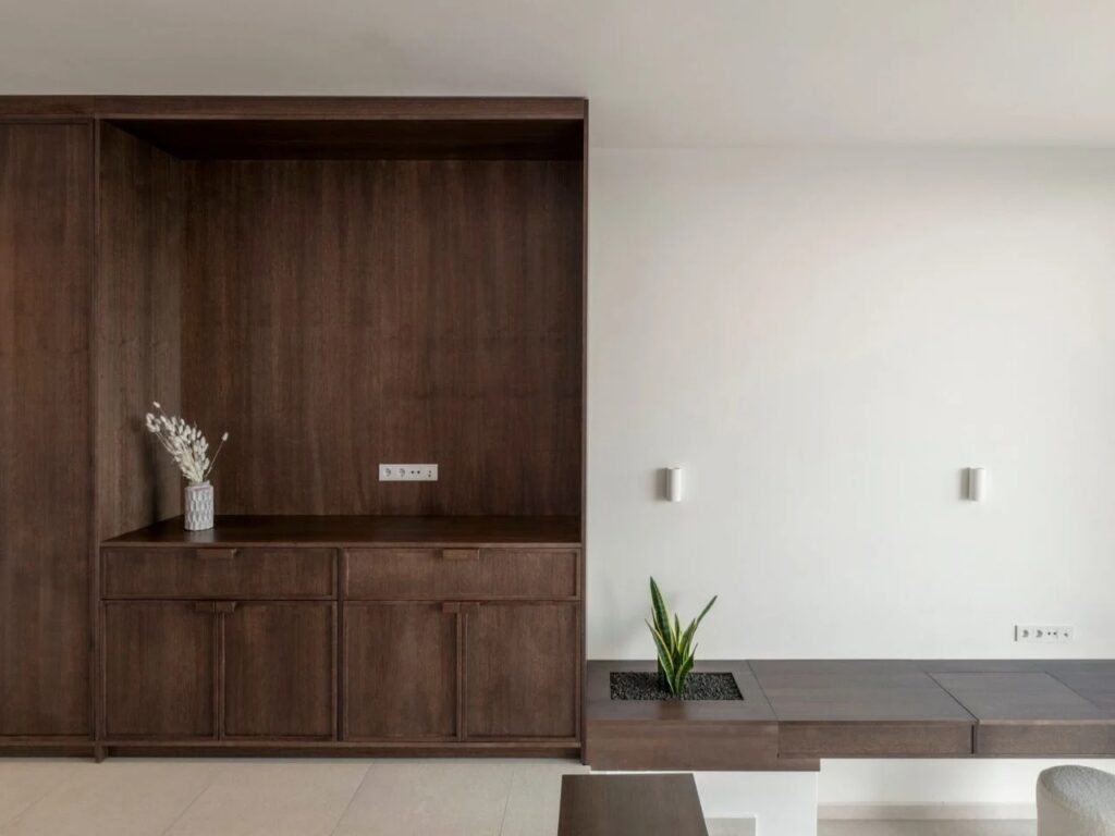 Interior detail showing dark wood cabinetry and a built-in planter with a green plant against a white wall.